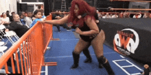 two women are wrestling in a wrestling ring in front of a crowd of people .