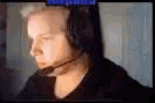 a man wearing headphones with a microphone on his head is sitting in front of a computer screen .