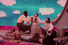 a group of men are gathered around a barrel with a pink cloth in the background