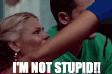 a woman is holding a man 's arm and says i 'm not stupid !