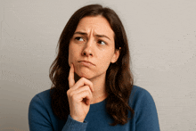 a woman in a blue sweater has her hand to her chin