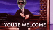 a man in a suit and tie is dancing in front of a sign that says you 're welcome