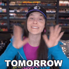 a woman wearing a hat says tomorrow with her hands up