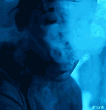 a man is smoking a hookah in a dark room and the smoke is coming out of his mouth ..