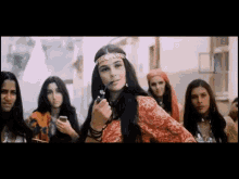 a group of women are standing around a woman smoking a pipe