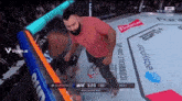 a man in a red shirt is standing in a boxing ring with budweiser advertisements on the walls