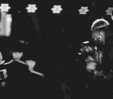 a black and white photo of a young man in a suit dancing on a stage .