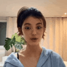 a young woman wearing glasses and a blue hoodie