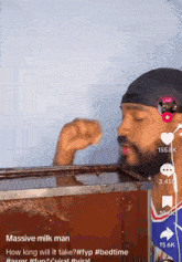 a man with a beard is drinking milk from a box