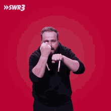 a man with a beard is giving the middle finger in front of a red background with swr3 written on it