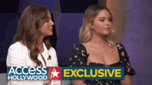 two women are sitting next to each other in front of an access hollywood banner