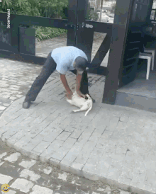 a man is petting a dog on a sidewalk with a smiley face on the bottom right
