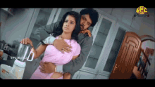 a man is hugging a woman in a kitchen with a tfc media logo on the bottom left