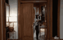 a woman in a witch costume is walking through a doorway with abc written on the bottom of the door