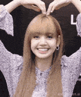 a woman is making a heart shape with her hands .