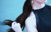 a woman in a black top is holding her hair in a ponytail