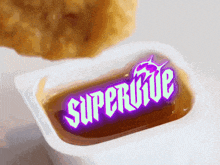 a packet of supervive sauce with a chicken nugget behind it