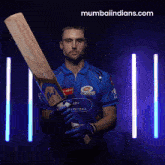 a man holding a cricket bat with the website mumbaiindians.com in the background