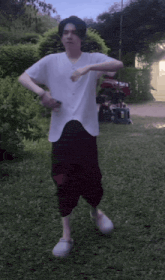 a man in a white shirt and burgundy pants is dancing in the grass