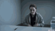 a woman is sitting at a desk with a pen and a bottle of water .