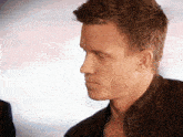 a man wearing a black leather jacket looks down