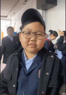 a boy wearing glasses and a jacket with the letter u on the collar