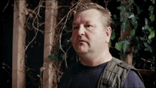 a man standing in front of a wooden fence with ivy on it