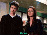 a man and a woman are standing next to each other and the woman is talking to the man .