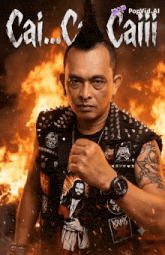 a man with a mohawk stands in front of a fire with the name cai.c. caii.i. written above him