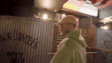 a man in a green hoodie is standing in front of a sign that says ' chase ' on it