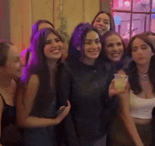 a group of young women are posing for a picture and one of them is holding a drink