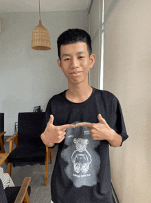 a young man is wearing a black shirt with a teddy bear on it that says supreme every day