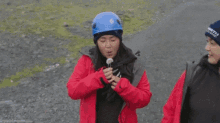 a woman wearing a north iceland hat holds a small object in her hand