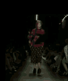 a model walks down a runway at a fashion show in front of a crowd
