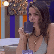 a woman in a tank top is drinking from a blue mug .