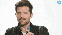 a man with a beard is holding a lollipop in his hand and making a face .