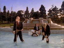 a group of men in suits are standing in a pool