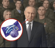 a man in a suit and tie is standing in front of a group of soldiers with a purple candy in front of him