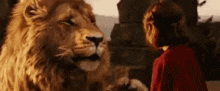 a woman in a red dress is standing next to a large lion .