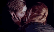 a man and a woman are kissing in a park .