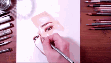 a person is drawing a woman 's face with a pencil on a piece of paper