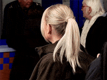 a woman with blonde hair in a ponytail stands in a crowd of people