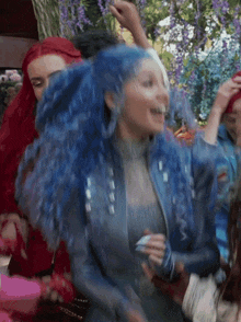 a woman with blue hair is dancing in front of a group of people