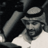 a man with a beard wearing a head scarf and a hat