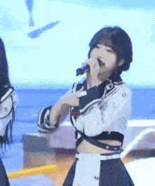a girl is singing into a microphone while wearing a school uniform
