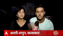 a man and a woman are sitting in front of a microphone and a sign that says aashi-shagun