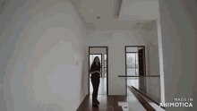 a woman is standing in an empty room with the words made in animotica on the bottom right