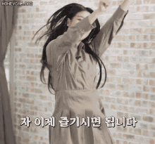 a woman in a dress is dancing in front of a brick wall with the words honeycam.org written above her
