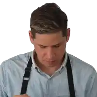 a man wearing a blue shirt and black suspenders is looking down
