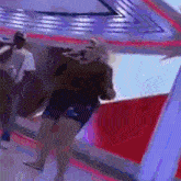 a woman in shorts and a black shirt is dancing in a room with purple lights